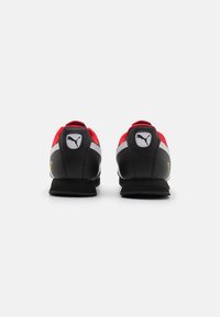 Chaussures de sport rouges et noires au design épuré, avec une tige texturée, des accents blancs et un logo bien visible sur le talon.