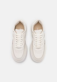 Ett par rena, vita lädersneakers med snören, perforerat tårområde och vadderad krage, visat från ovan på en vit bakgrund.