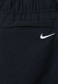 Črne Nike kratke hlače z elastiko v pasu, z zadnjim žepom in belim vezenim logotipom na spodnji levi strani. Gladka tekstura.