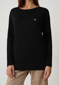 Maglione nero a maniche lunghe realizzato in tessuto lavorato a maglia, con scollatura rotonda e una piccola bandiera norvegese ricamata sul petto.