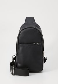 Black faux leather backpack with a rounded shape, silver zipper, front pocket, and adjustable fabric strap. Smooth texture with logo detail.