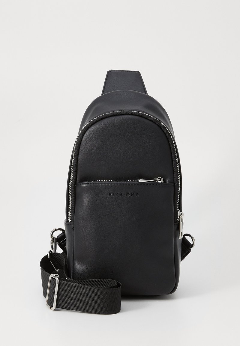 Black faux leather backpack with a rounded shape, silver zipper, front pocket, and adjustable fabric strap. Smooth texture with logo detail.