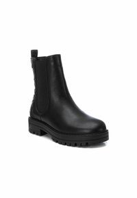 Bota de cuero negro hasta el tobillo con paneles elásticos laterales y un acabado texturizado. Suela gruesa de goma con surcos profundos para tracción.