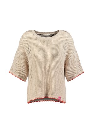 Pull tricoté beige à manches courtes, coupe ample, col rond, bordures rouges festonnées aux manches et à l’ourlet, et petite étiquette rose près de l’ourlet inférieur.