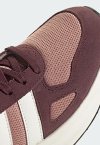 Tenisky s burgundským semišovým a síťovaným svrškem, bílými koženými pruhy, texturovaným povrchem a černou gumovou podrážkou.