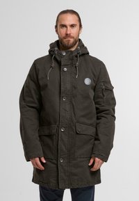Olivgrüne Parkajacke aus gewebtem Stoff, mit einer Kapuze, Knopfverschluss, zwei Fronttaschen und einer Reißverschlusstasche am Ärmel.