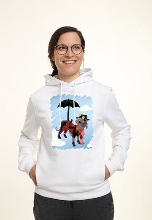 Smilende kvinde med briller og hvid hættetrøje med en tegnet mops, der svæver med en paraply på en blå himmel med skyer.