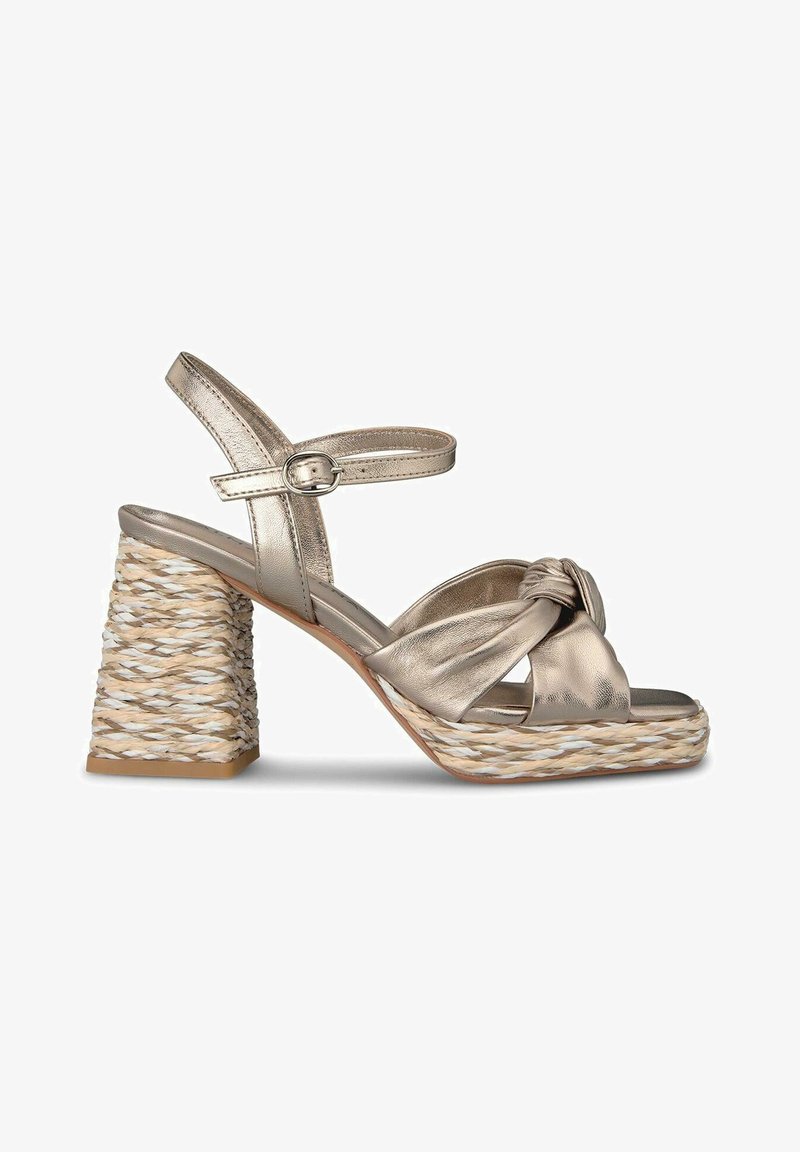 Metallic gold heeled sandals with a knotted front design, featuring a woven textured block heel in natural tones and an adjustable ankle strap.