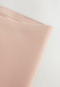 Roze stof met een gladde textuur, onder een hoek gevouwen. Het materiaal lijkt licht van gewicht, met een lichte glans en subtiele rek.