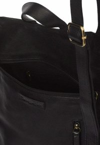 Bolso de hombro de cuero negro con apertura superior con cremallera, correa ajustable con hebilla de latón y un bolsillo exterior con cremallera.