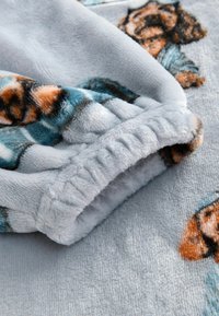 Tejido de forro polar gris suave con puño elástico fruncido y osito de peluche impreso con ropa azul en la superficie y la manga.
