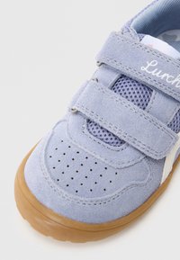 Modrá semišová teniska s panelmi z sieťoviny, suchými zipsami, perforovanou špičkou a svetlohnedou gumovou podrážkou. Názov značky "Lurchi" vyšitý na remienku.