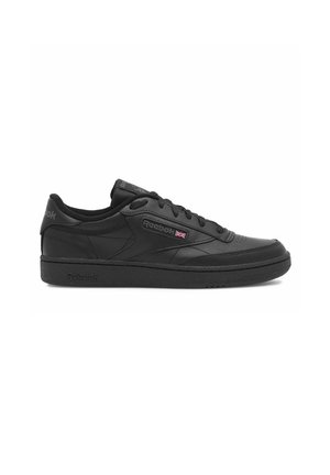 Zapatilla baja negra de Reebok con cordones delanteros, suela texturizada y logo de Reebok con una pequeña bandera británica en el lateral.
