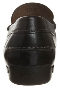 Zwarte leren instappers met een afgeronde achterkant, decoratieve stiksels en een rubberen zool met het "GEOX" logo op de hak.