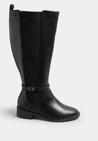 Schwarze knähöga stövlar med en slät läderutsida och tygpaneler på sidorna. Har en spänndetalj och en låg blockklack.