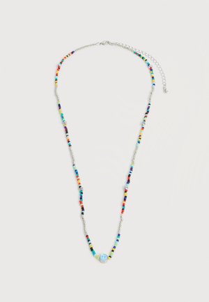 Ασημένιο κολιέ με πολύχρωμες χάντρες και μια κεντρική μπλε χάντρα με ένα χαμογελαστό πρόσωπο, με ρυθμιζόμενο προεκτάσιμο κούμπωμα.