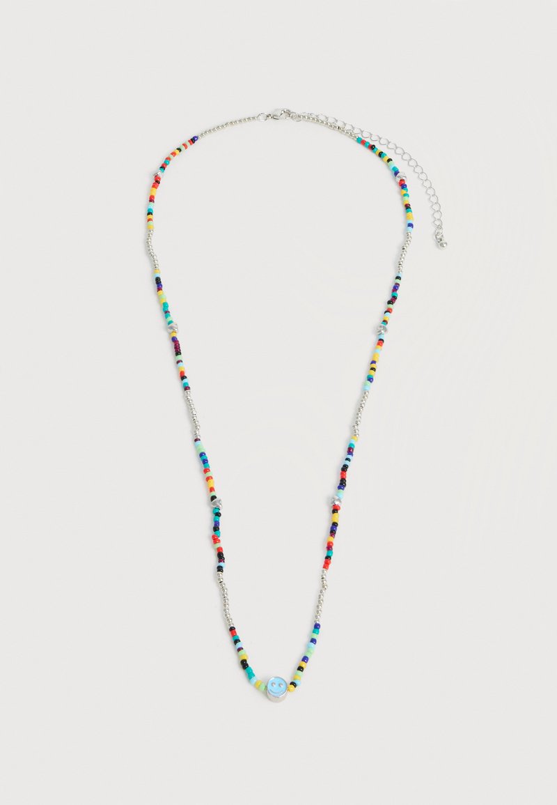 Ασημένιο κολιέ με πολύχρωμες χάντρες και μια κεντρική μπλε χάντρα με ένα χαμογελαστό πρόσωπο, με ρυθμιζόμενο προεκτάσιμο κούμπωμα.