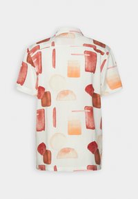 Chemise blanche à manches courtes avec des formes géométriques abstraites rouges, orange et beige imprimées sur tout le tissu.