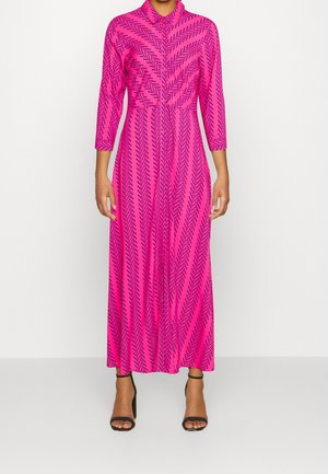 Fuchsia lange mouwen jurk met een chevronpatroon, voorzien van een kraag en een vloeiende silhouet, gecombineerd met zwarte sandalen met hak.