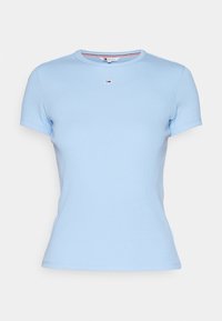 Jasnoniebieska dopasowana koszulka z krótkim rękawem, wykonana z prążkowanego dzianego materiału, z okrągłym dekoltem i małą czerwoną, białą oraz granatową naszywką z logo umieszczoną centralnie pod kołnierzem.