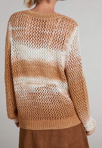 Pull en crochet à mailles ouvertes, présentant un dégradé de pêche à crème. Ourlet et poignets côtelés, manches longues et tricot texturé.