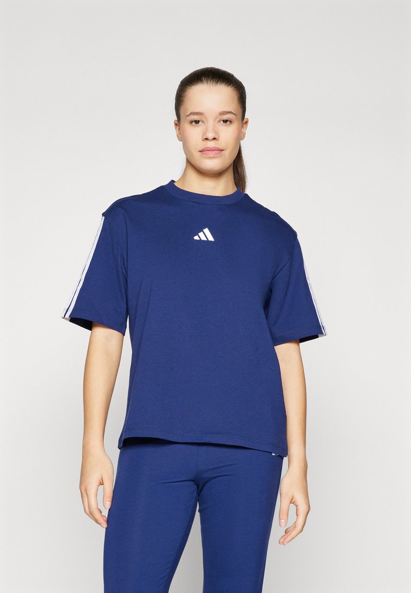 Tamsiai mėlyna medvilninė marškinėliai trumpomis rankovėmis, su apvalia iškirpte ir balta Adidas logotipu ant krūtinės. Suderinti su atitinkančiomis tamsiai mėlynomis leggingais.