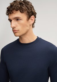 Navyblaues Sweatshirt mit rundem Rundhalsausschnitt, langen Ärmeln und glatter Textur. Einfaches Design ohne sichtbare Muster oder Akzente.