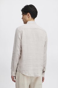 Lys beige lin skjorte med knapp ned-krage, mansjetter med enkelt knapp, og buet kant, med en teksturert stoffdetalj.