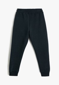 Pantalones deportivos negros con cintura elástica y puños acanalados, ajuste recto y sin bolsillos ni logotipos visibles, exhibidos de forma plana sobre un fondo blanco.