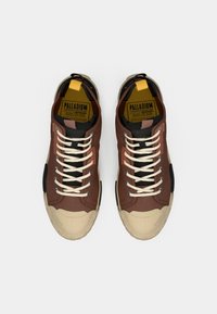 Καφέ ύφασμα αθλητικά παπούτσια με μπεζ λαστιχένιες σόλες, λευκά κορδόνια και κίτρινη ετικέτα. Διαθέτουν μαύρες λεπτομέρειες και υλικά με υφή.