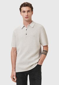 Lichtgrijze polo met korte mouwen van structuurnylon, met een kraag, een sluiting met drie knopen en een subtiele logo op de borst.