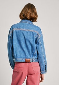 Jeans jakna u svijetloplavoj boji s uskim prošivom na gornjem dijelu leđa, s smeškim kožnim detaljima na struku i gumbima za zatvaranje.