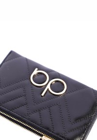 Cartera de cuero negra con patrón acolchado, herrajes dorados y un logo. Cuenta con cierre de cremallera y superficie texturizada.