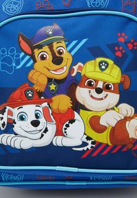 Mėlyna kuprinė su animaciniais šunimis, turinčiais ryškias juodas ir baltas dėmes. Dizainas apima pėdų antspaudus ir ženklelius, pagaminta iš patvarios medžiagos.