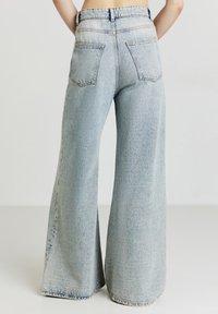 Jeans in denim azzurro chiaro a vita alta e gamba larga. Presentano cinque tasche e un motivo di cucitura classico lungo le cuciture.