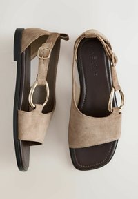 Sandales plates en daim beige avec bride réglable, détail boucle dorée et semelle intérieure rembourrée marron foncé, vues de dessus et de côté.