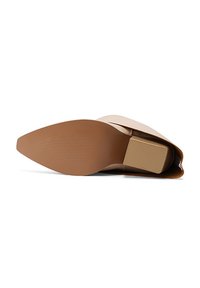 Zapato beige de punta con tacón bajo tipo bloque, material superior liso y suela texturizada para mayor agarre. Presenta un diseño elegante y minimalista.