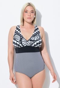 Maillot de bain noir et blanc avec un motif floral et en zigzag sur le haut, accompagné d'une bande noire unie et d'une texture rayée sur la partie inférieure.