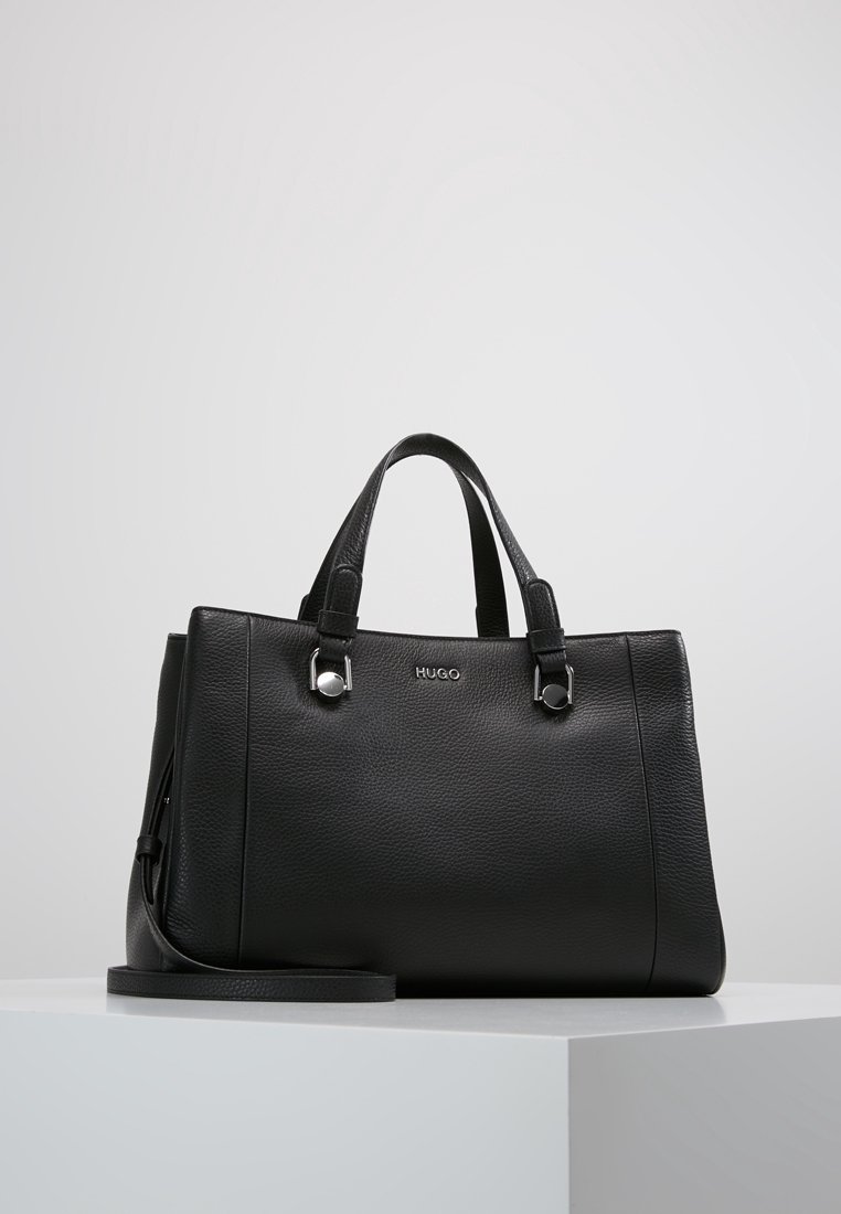 Czarna skórzana torebka z dwoma górnymi uchwytami, srebrnymi akcentami, fakturowanym wykończeniem i odpinanym paskiem na ramię. Logo widoczne na przodzie.