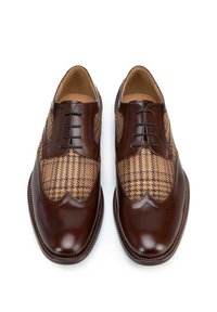 Chaussures en cuir marron avec un tissu à motif tissé marron et beige sur la tige, dotées d'un bout lisse et de cinq œillets pour le laçage.