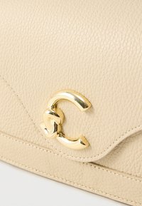 Μπεζ δερμάτινη τσάντα χειρός με αγκράφα σε χρυσό τόνο, διακοσμημένη με διαπλεκόμενο λογότυπο και εμφανή υφή στην επιφάνεια. Ράψεις κατά μήκος των άκρων.