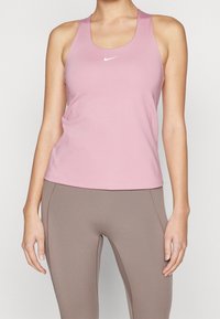 Nike atletisk tanktop i lyserød med rund hals og racerback-design. Glat tekstur, logo på brystet, kombineret med beige leggings.