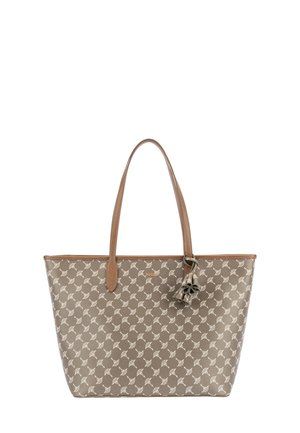Sac cabas marron avec motif floral beige clair, deux longues anses en cuir et un pendentif fleur décoratif près de la base de l'anse.