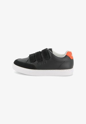 Baskets en cuir noir avec trois lanières Velcro, semelle en caoutchouc blanche et un accent orange au talon. Présentent un bout arrondi et une texture lisse.