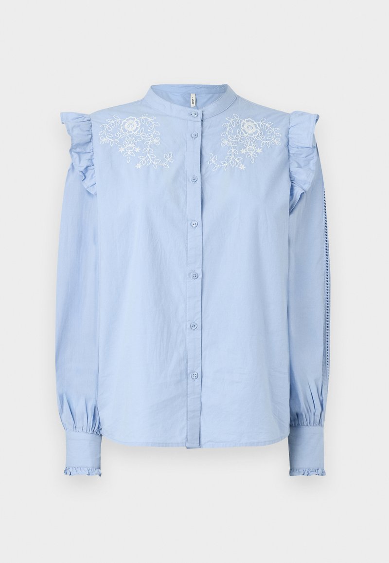 Chemise bleu clair à manches longues avec détail volanté aux épaules et broderies florales sur la poitrine. Présente des poignets froncés.