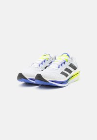 White athletic shoes with a textured mesh upper, black accents, and neon yellow and blue details. Features a cushioned sole for comfort.