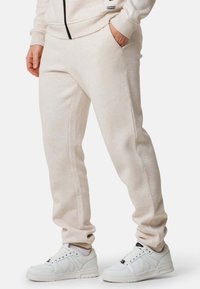 Ljust beige mjukisbyxor i mjukt tyg, med en tapered design, sidfickor och i kombination med vita sneakers.