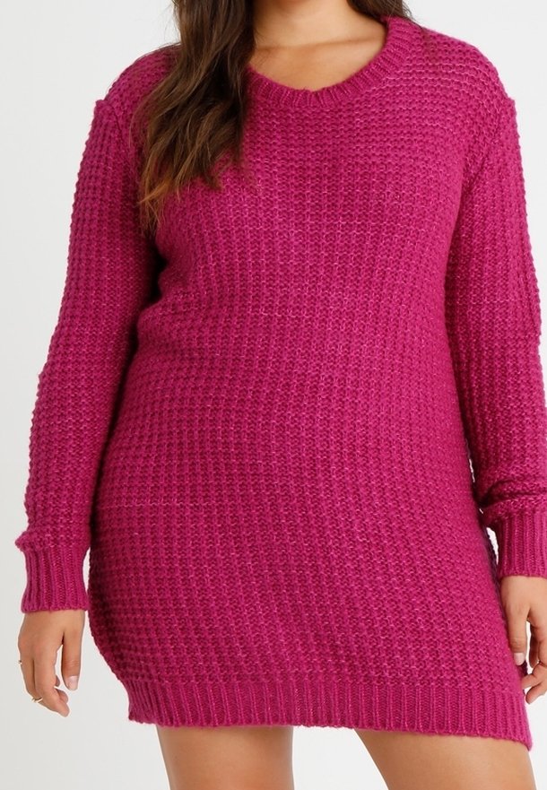 Femme portant une robe-pull magenta en maille texturée à manches longues, debout les bras détendus le long du corps.