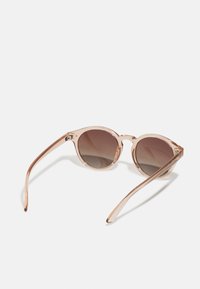 Round sunglasses with a translucent pink frame, dark gradient lenses, and sleek, thin arms. No visible logos or embellishments.
