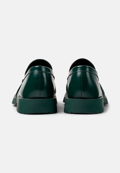 Grüne Lederschuhe mit glatter Oberfläche, runder Form und dicken Gummisohlen. Sie verfügen über dezente Nähte und ein minimalistisches Design.